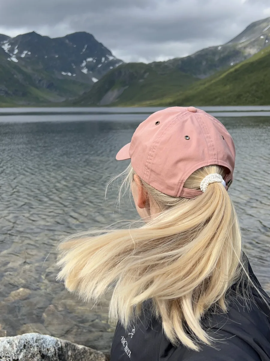 Viktoria, the faceless creator behind SimpleFacelessStudio, seen from behind by a mountain lake